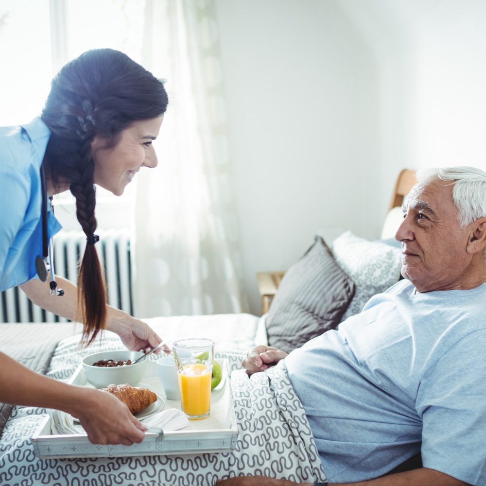 nurse serving breakfast to senior man